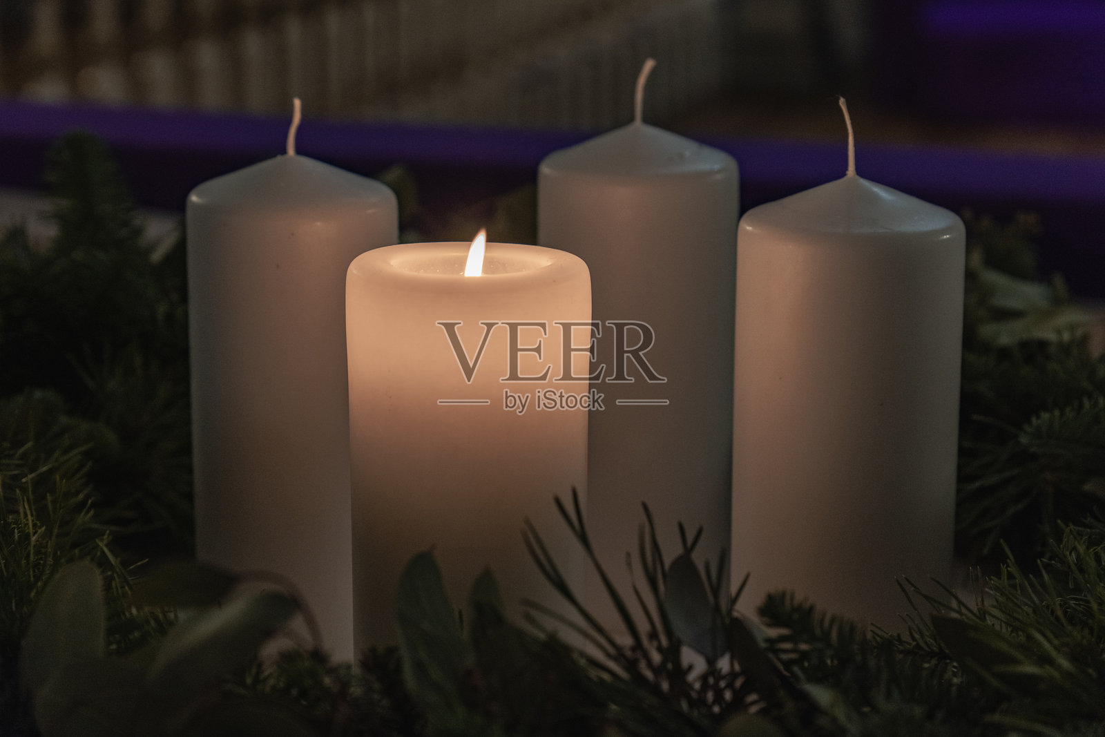 特写：带有已点燃蜡烛的降临节花环，周围环绕着常绿植物照片摄影图片