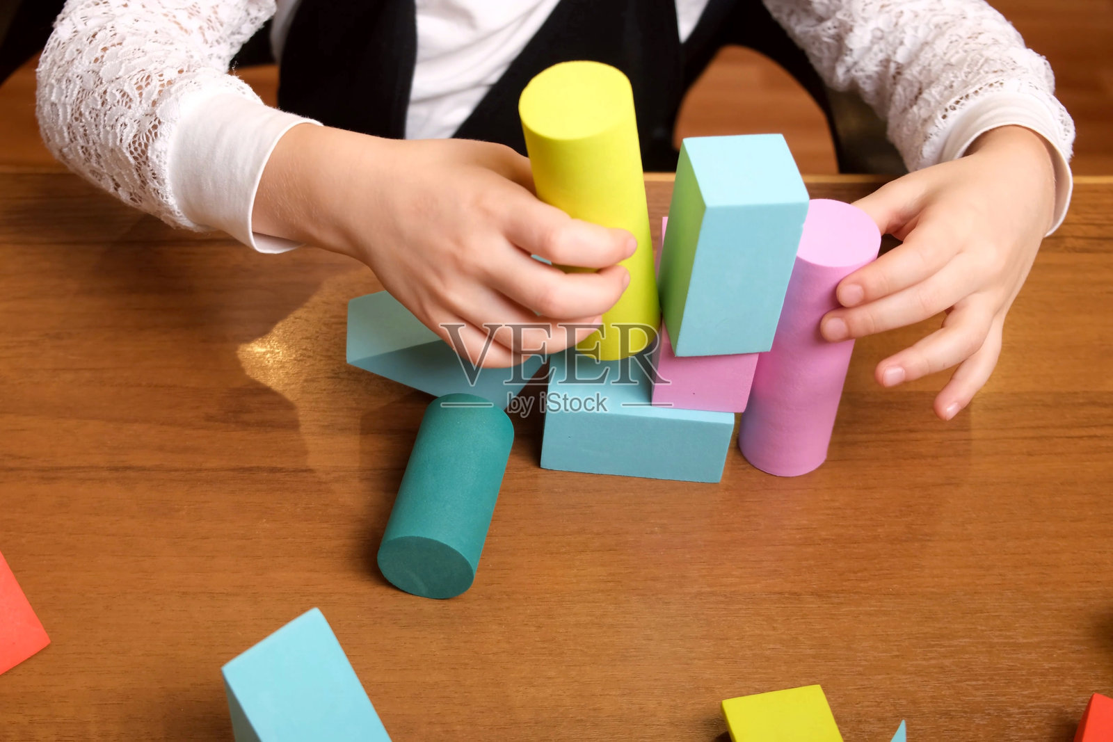 小女孩的手用柔和的粉彩色积木搭建不稳的塔照片摄影图片