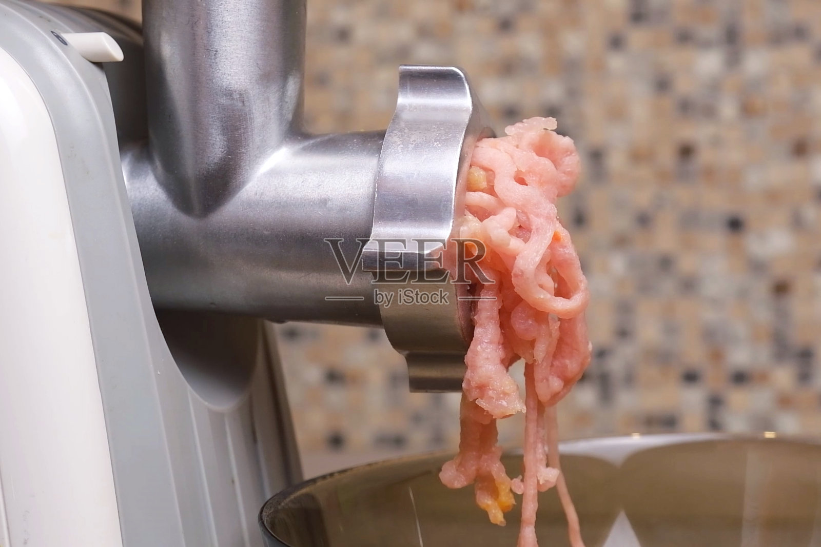 粉色肉末从电动绞肉机缓慢流入碗中照片摄影图片