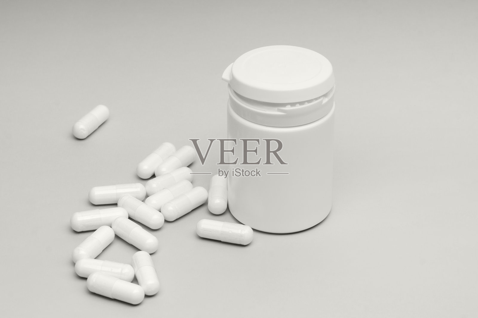 白天，灰色的表面上散落着胶囊的白色胶囊容器照片摄影图片