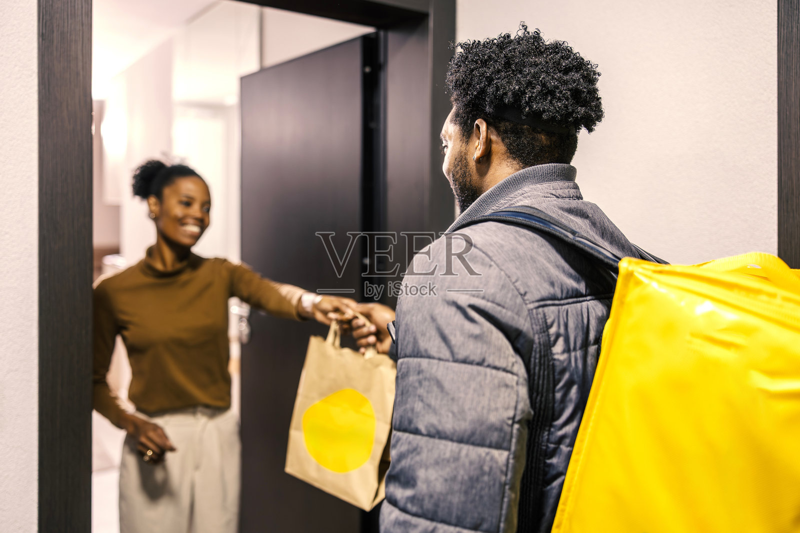 送餐员在门口将食品订单递给女士照片摄影图片