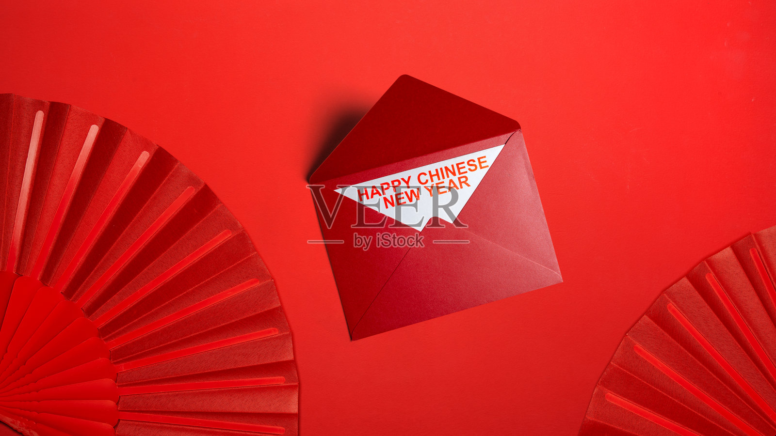 红色背景上的红包和中国新年祝福折扇。农历新年或中国新年快乐庆典照片摄影图片
