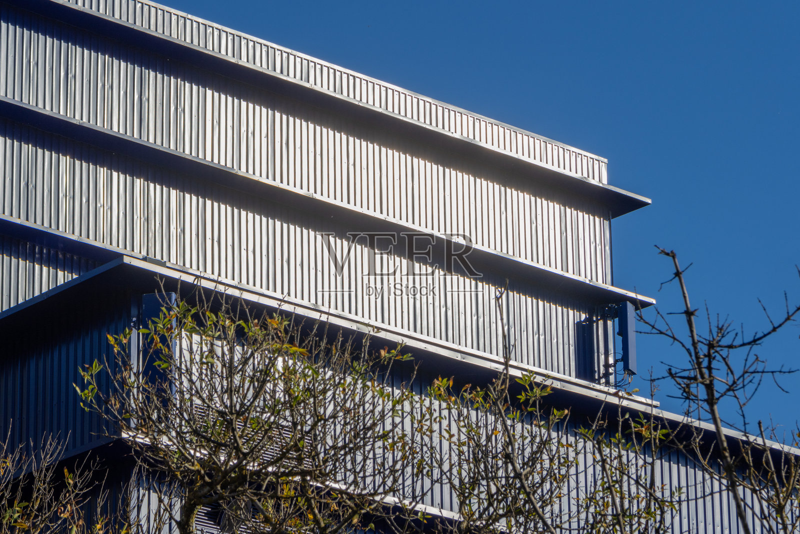 卡蒙斯剧院的金属外墙,配以树木和蓝天照片摄影图片