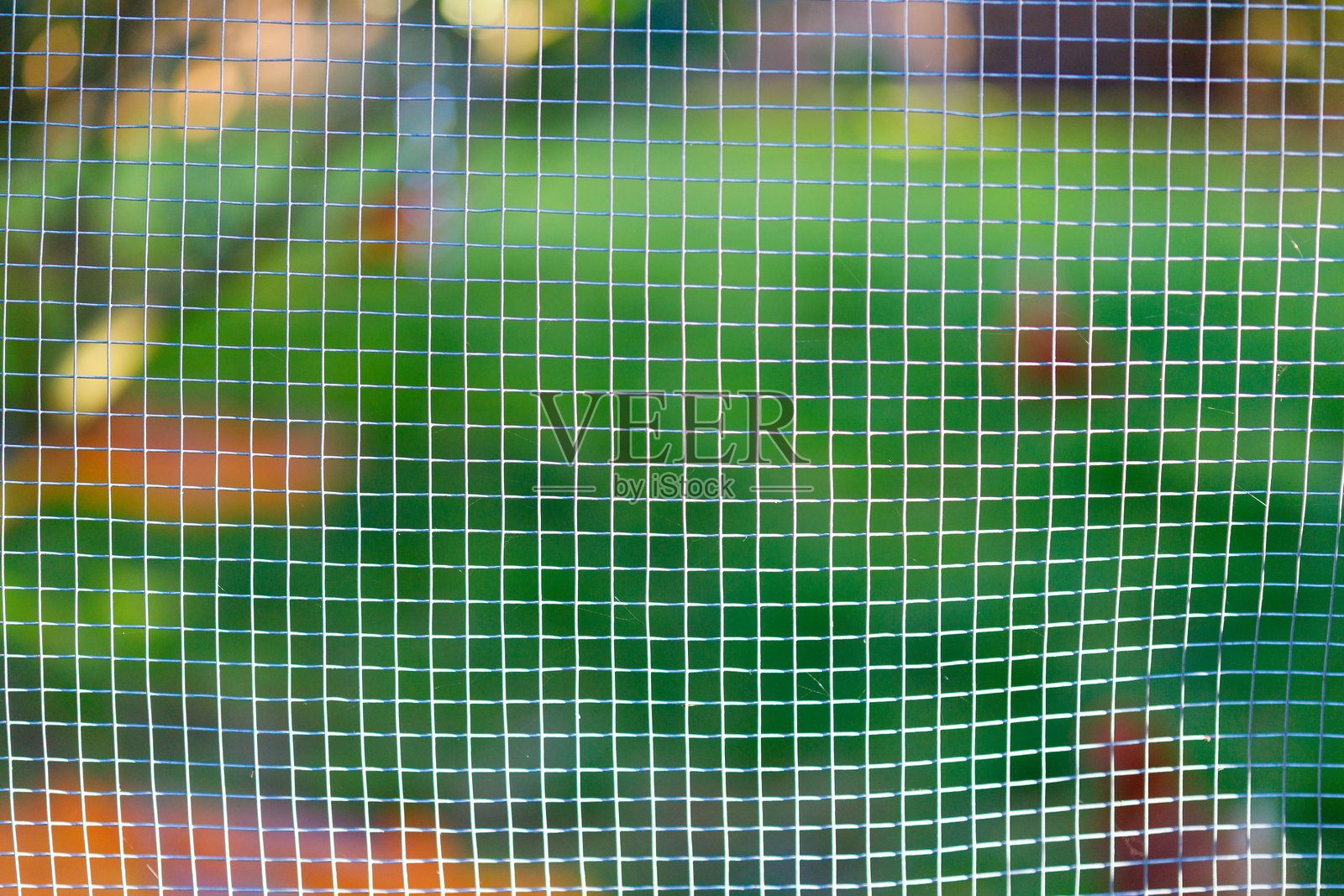 模糊的绿橙色背景上的金属丝网照片摄影图片