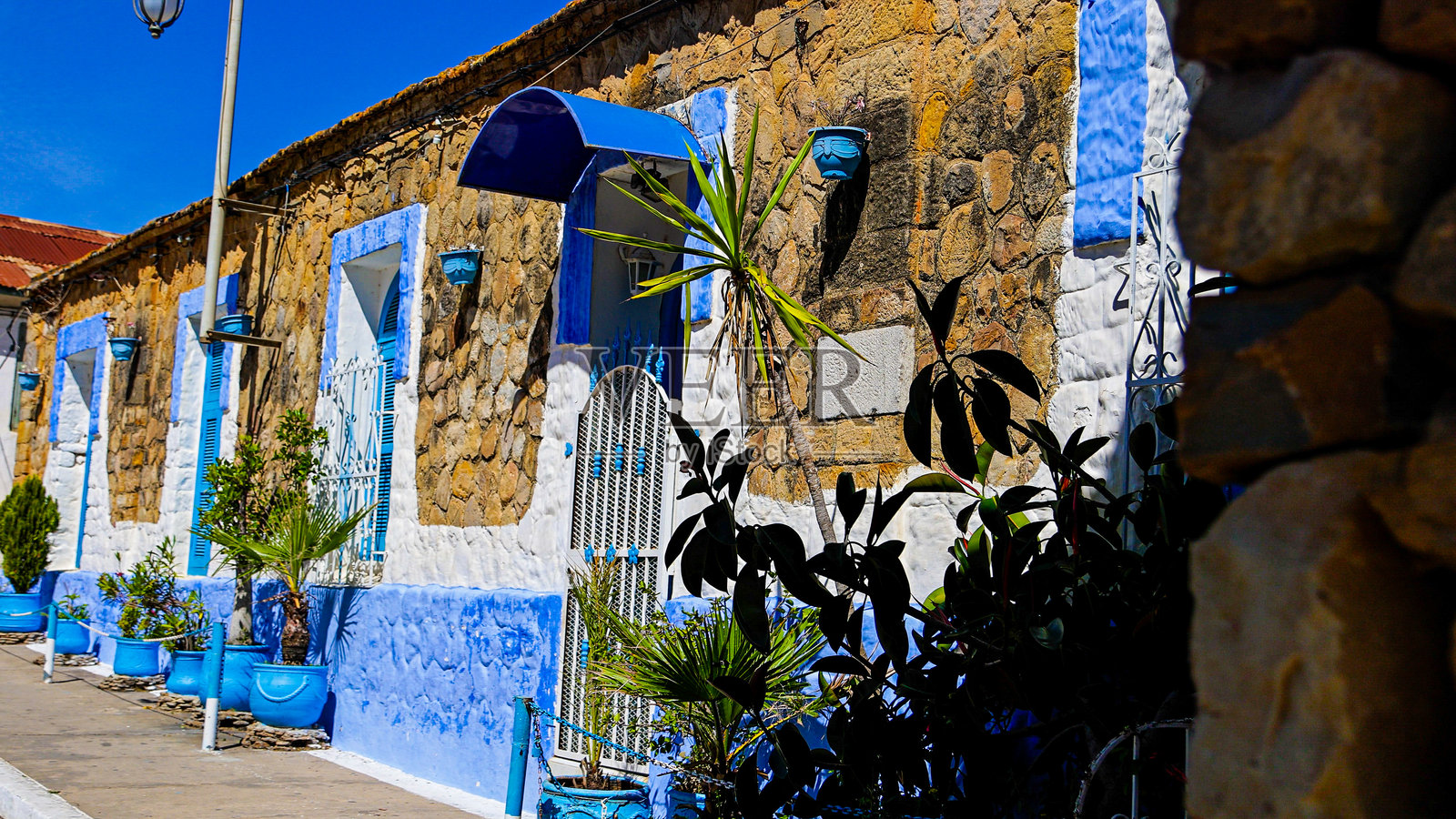 摩洛哥北部阿西拉麦地那传统石屋的街景，拥有蓝白彩绘外墙和拱形门，地中海建筑和文化旅游概念，适用于旅行设计和编辑用途照片摄影图片