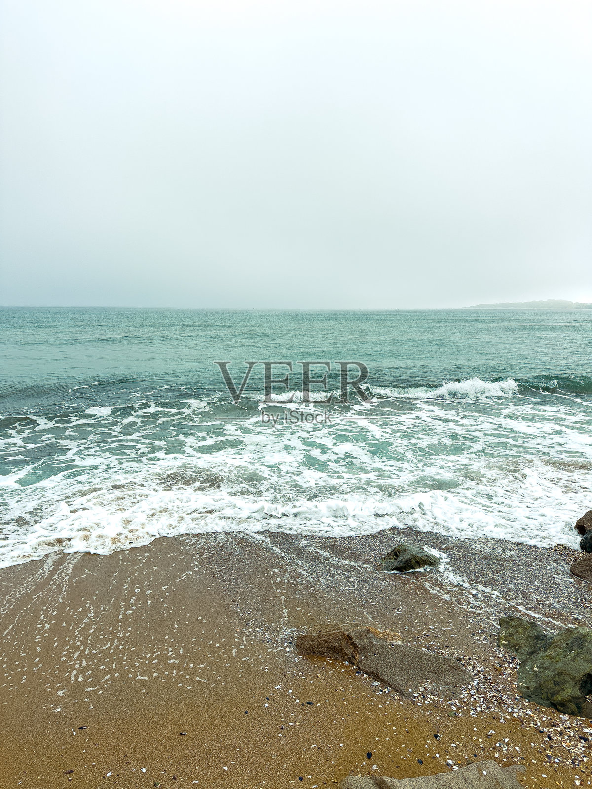 阴天午后，海浪拍打着海岸线照片摄影图片