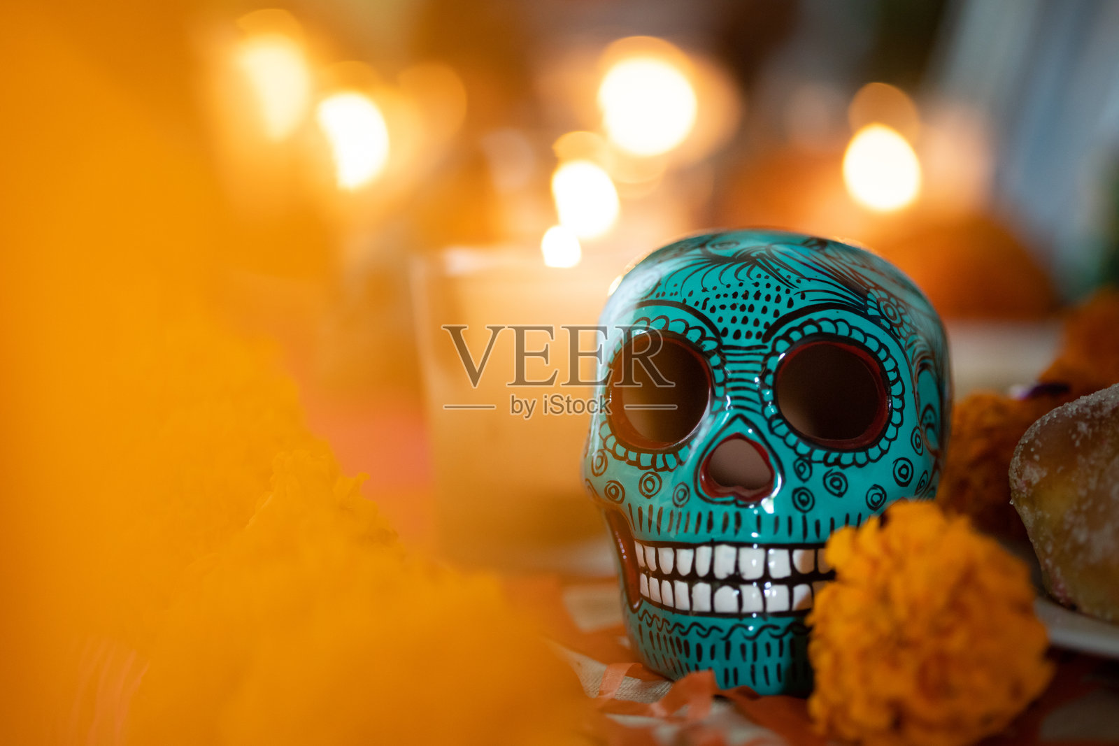 亡灵节祭坛，摆放着蜡烛、墨西哥亡灵节面包、万寿菊和陶瓷骷髅头照片摄影图片