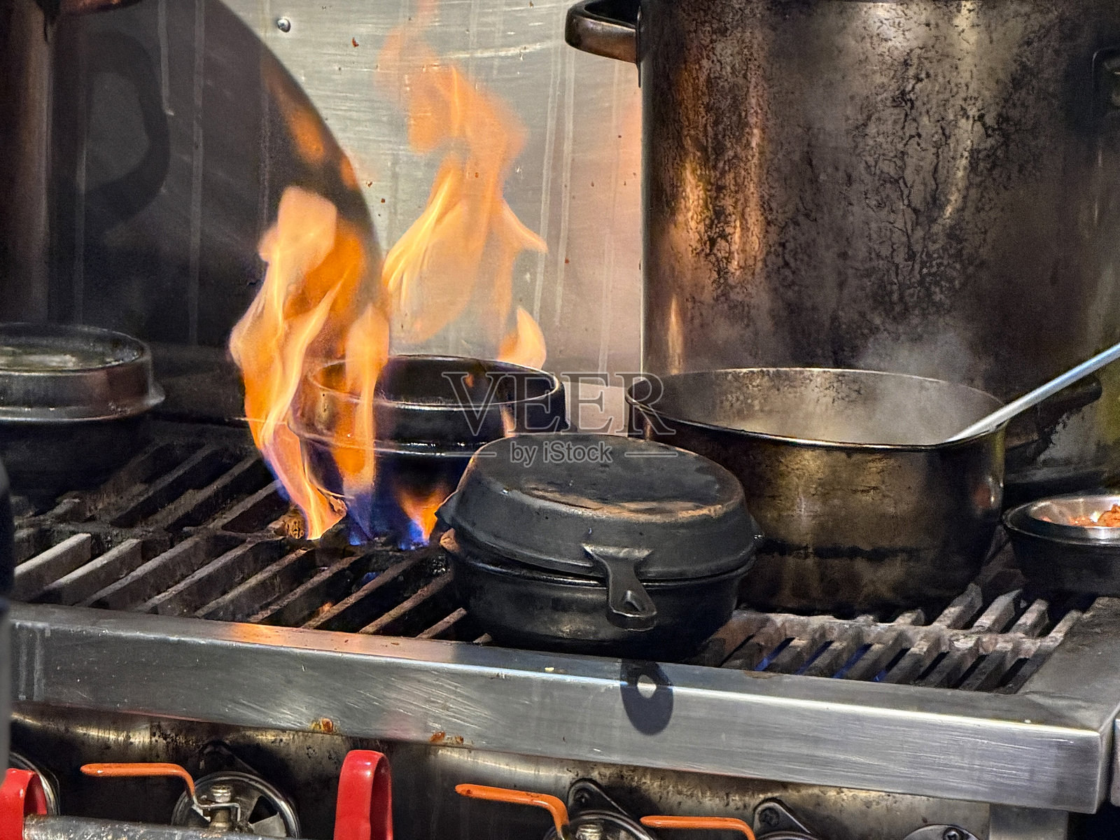 燃气灶火焰在装满油的煎锅上熊熊燃烧，厨房烹饪危险，高温煎炸风险，食物滋滋作响，潜在火灾隐患照片摄影图片