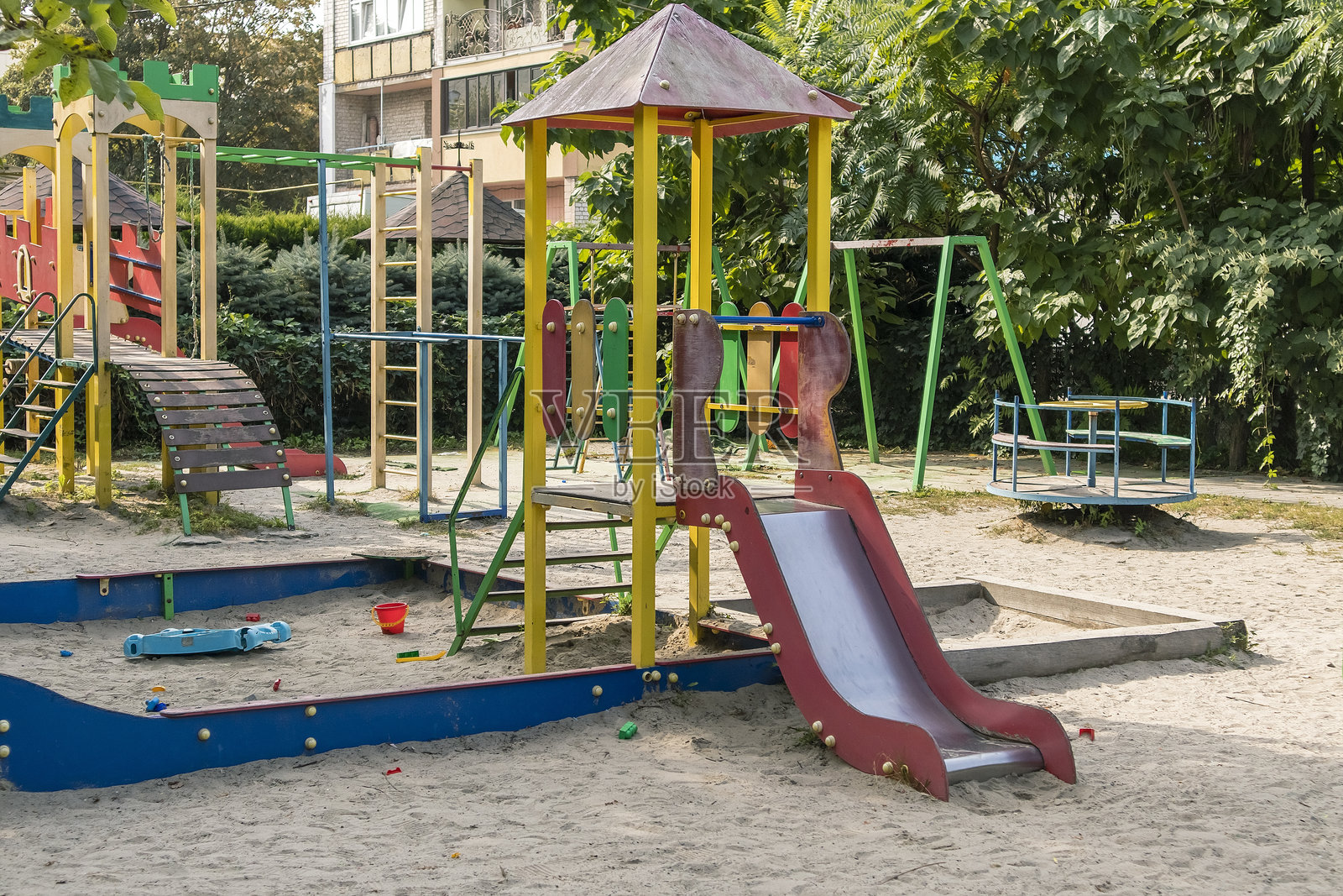 一个色彩鲜艳的儿童游乐场，配有滑梯、攀爬架和沙坑，静静地坐落在一个宁静的居民庭院中，象征着城市家庭的休闲娱乐。照片摄影图片