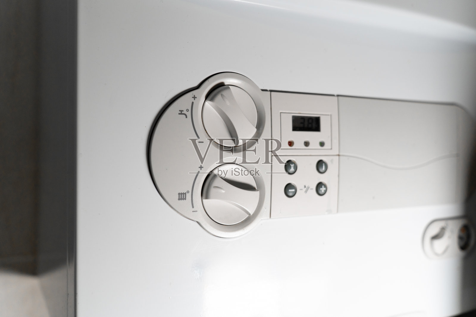 一个人在家用锅炉控制面板上调节温度设置。特写镜头突出了供暖调节、能源效率和现代家用设备。照片摄影图片