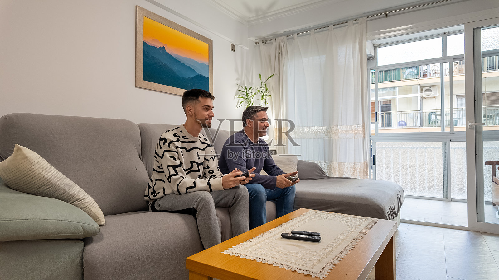 父亲和儿子在家一起玩电子游戏，增进感情照片摄影图片