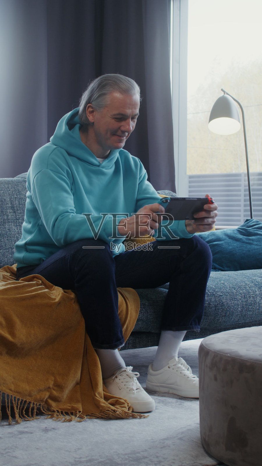 男人坐在沙发上玩掌上游戏机 - 游戏照片摄影图片