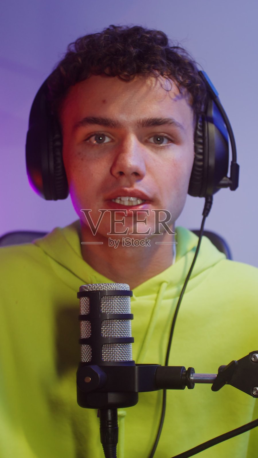 戴着耳机的年轻男子正在对着麦克风说话，游戏照片摄影图片