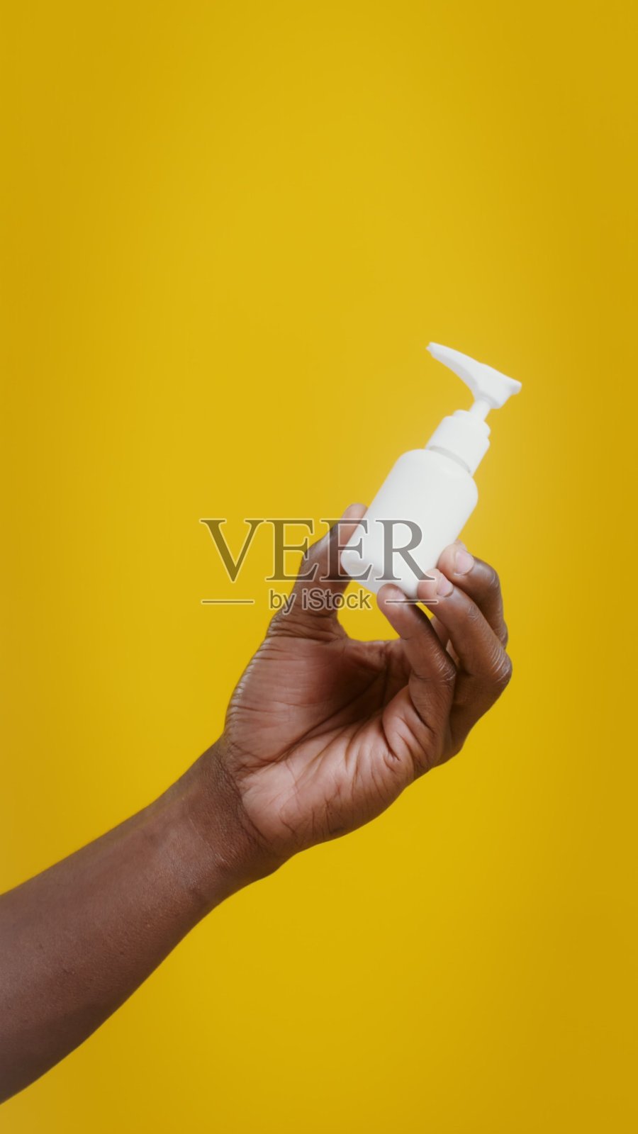 一只男人的手拿着一个写着“Care”的白色瓶子照片摄影图片