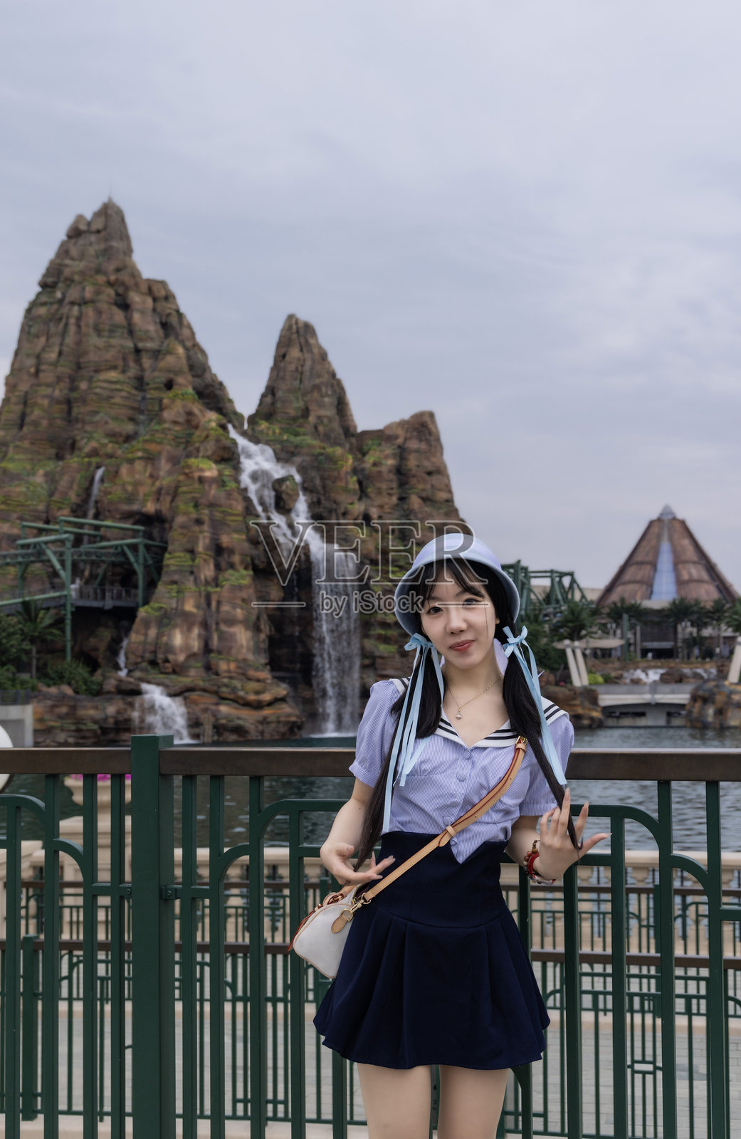 年轻女孩站在岩石瀑布旁照片摄影图片