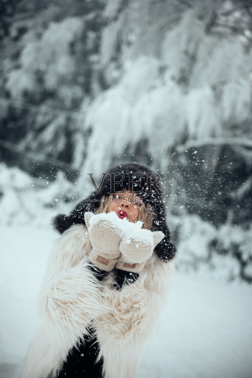 年轻人在被树木和降雪环绕的冬季景观中玩雪照片摄影图片