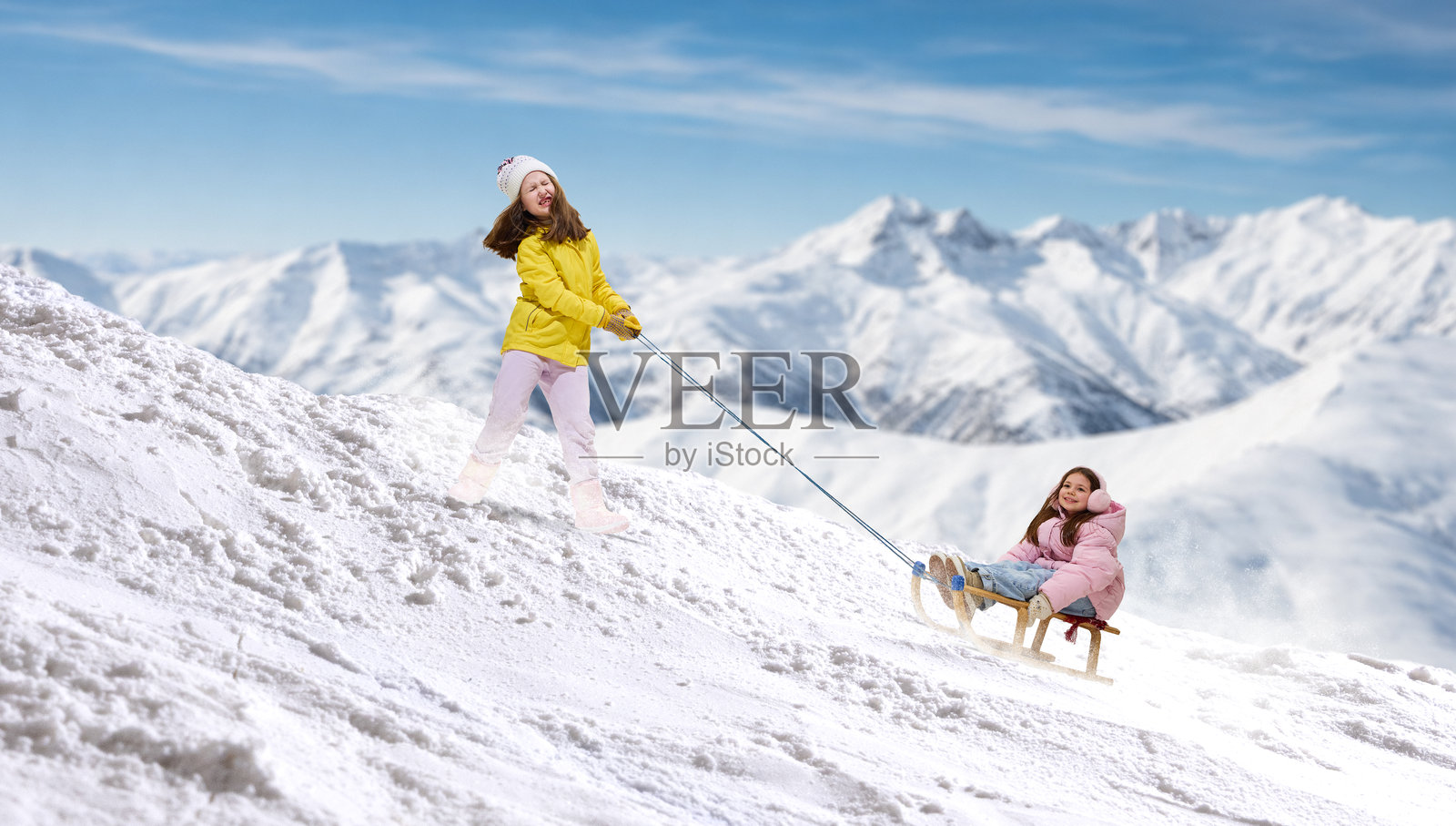 温馨的艺术作品，描绘女孩在山坡上拉着载有微笑孩子的雪橇。照片摄影图片