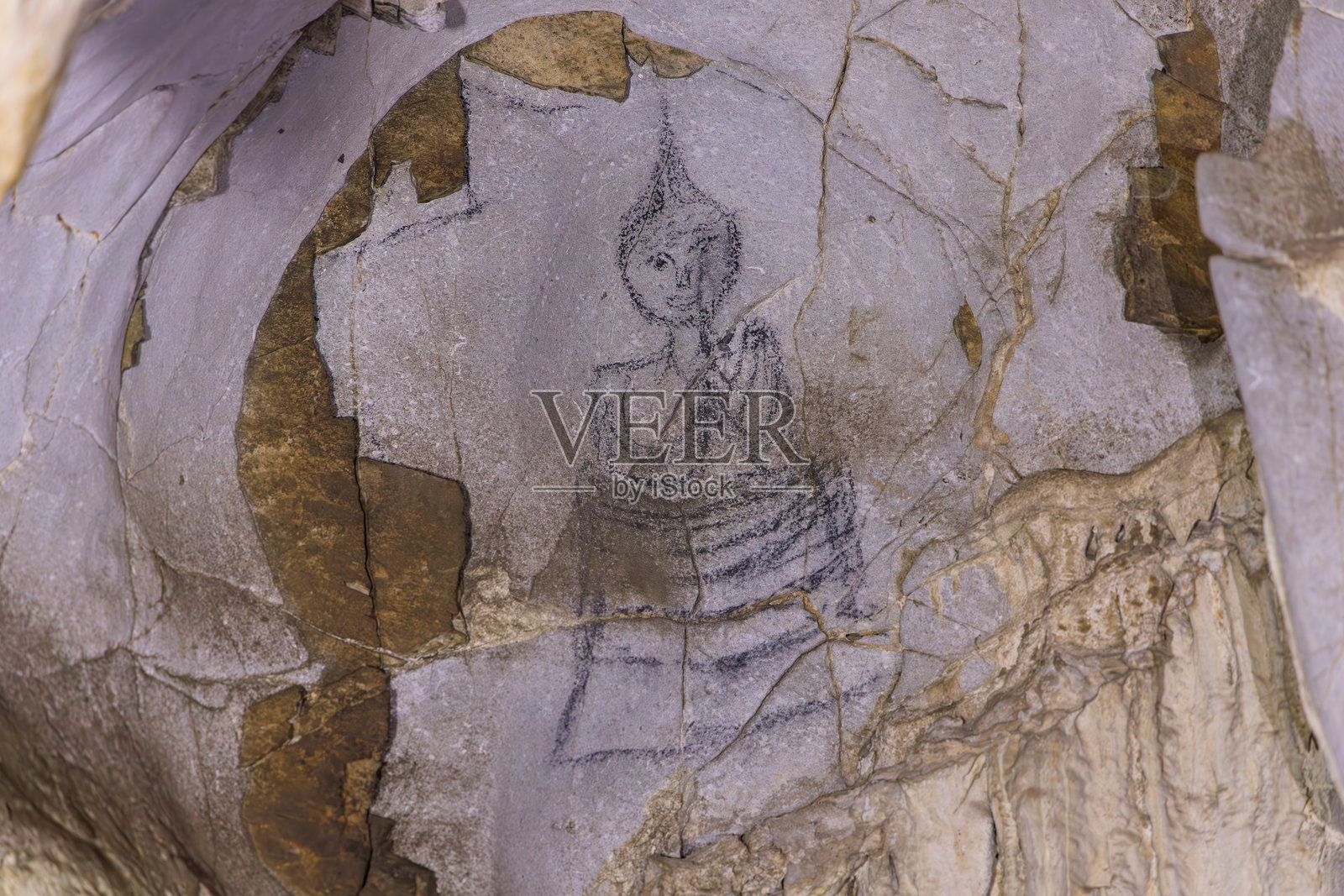 泰国考艾（Khao Yai）粗糙洞穴墙壁上坐佛的古代岩画，表面有风化矿物质照片摄影图片