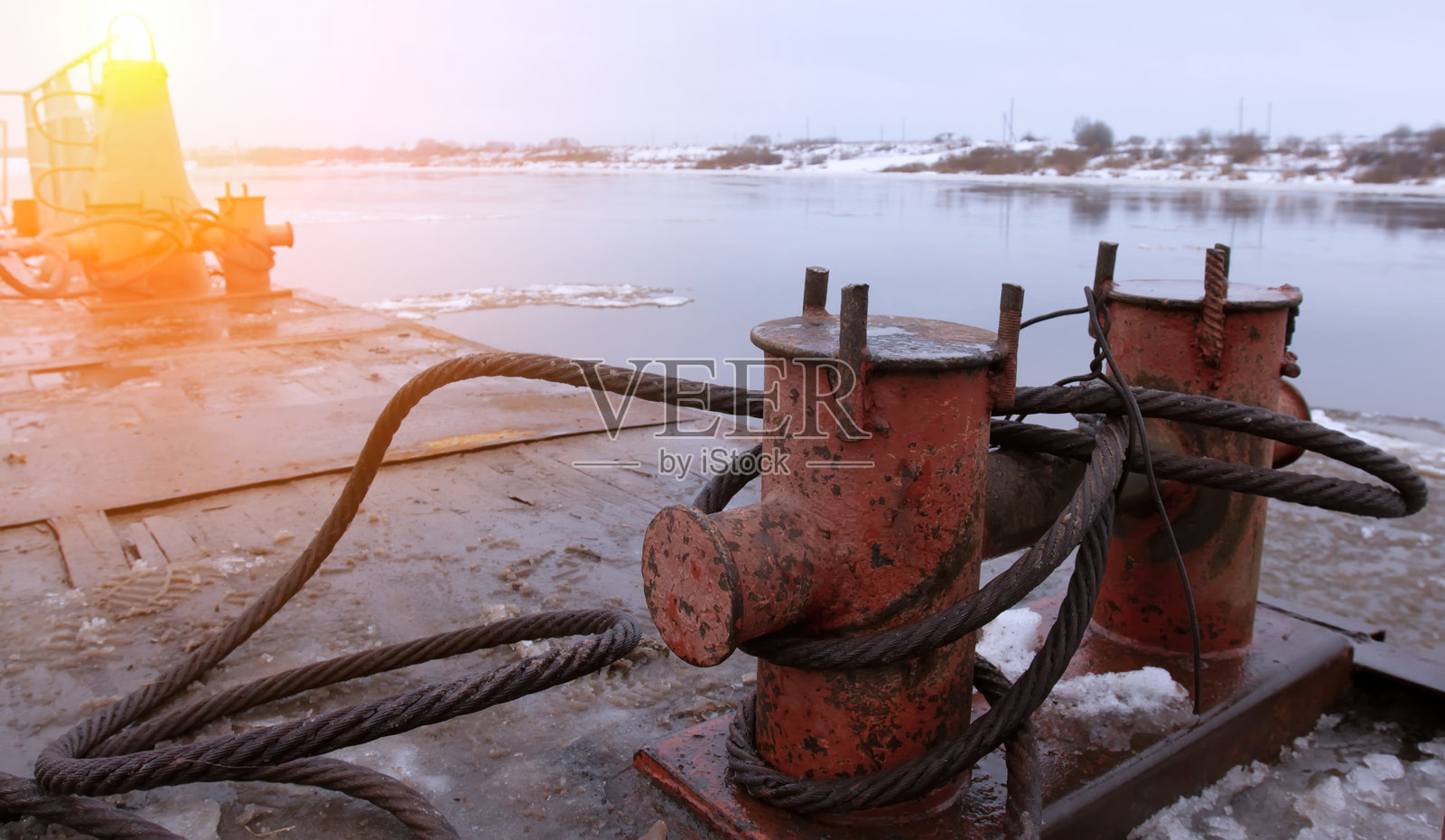 河岸边用于船只停泊的工业设备，背景是日落时的冬季景色照片摄影图片