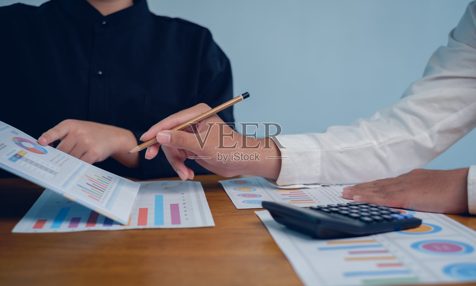 商务人士在办公桌上分析带有图表、图形和计算器的财务报告，体现了财务分析、预算、规划、审计、战略和决策的专业团队合作理念。照片摄影图片