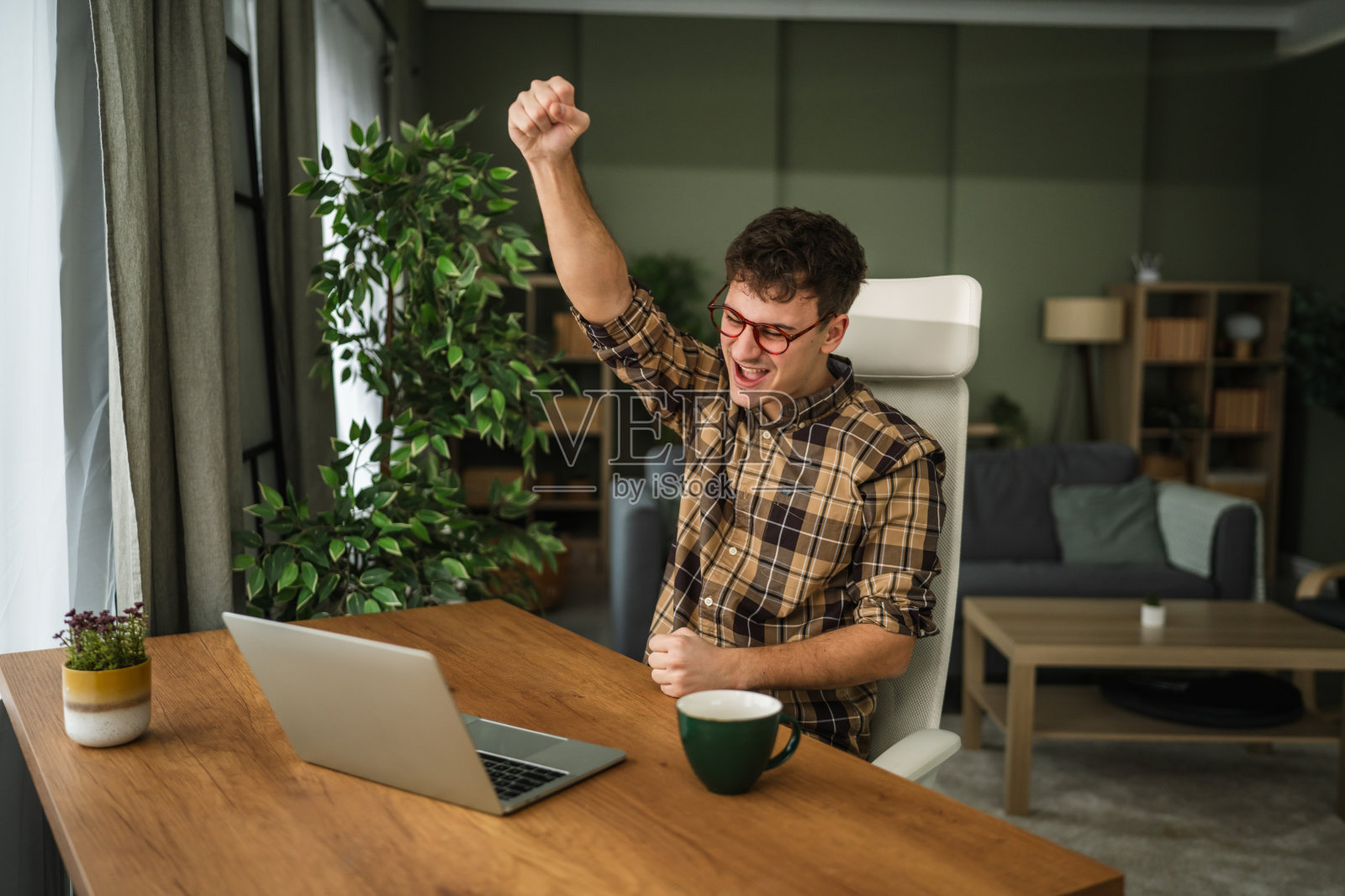 年轻男子在家中成功庆祝，同时使用笔记本电脑工作照片摄影图片