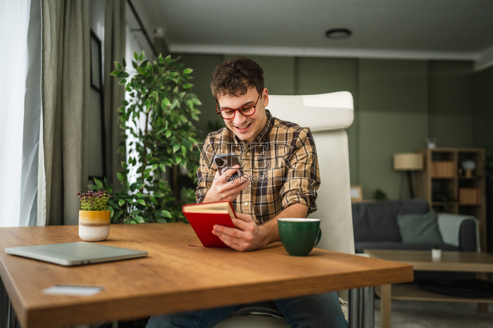 年轻人一边拿着书一边玩手机照片摄影图片