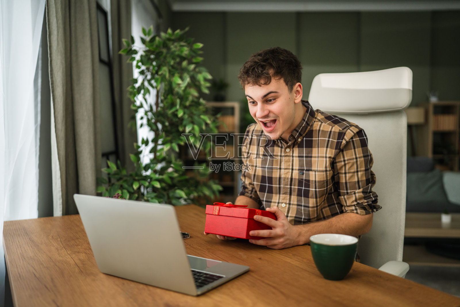 男子通过笔记本电脑在网上惊喜地收到礼物，十分兴奋照片摄影图片