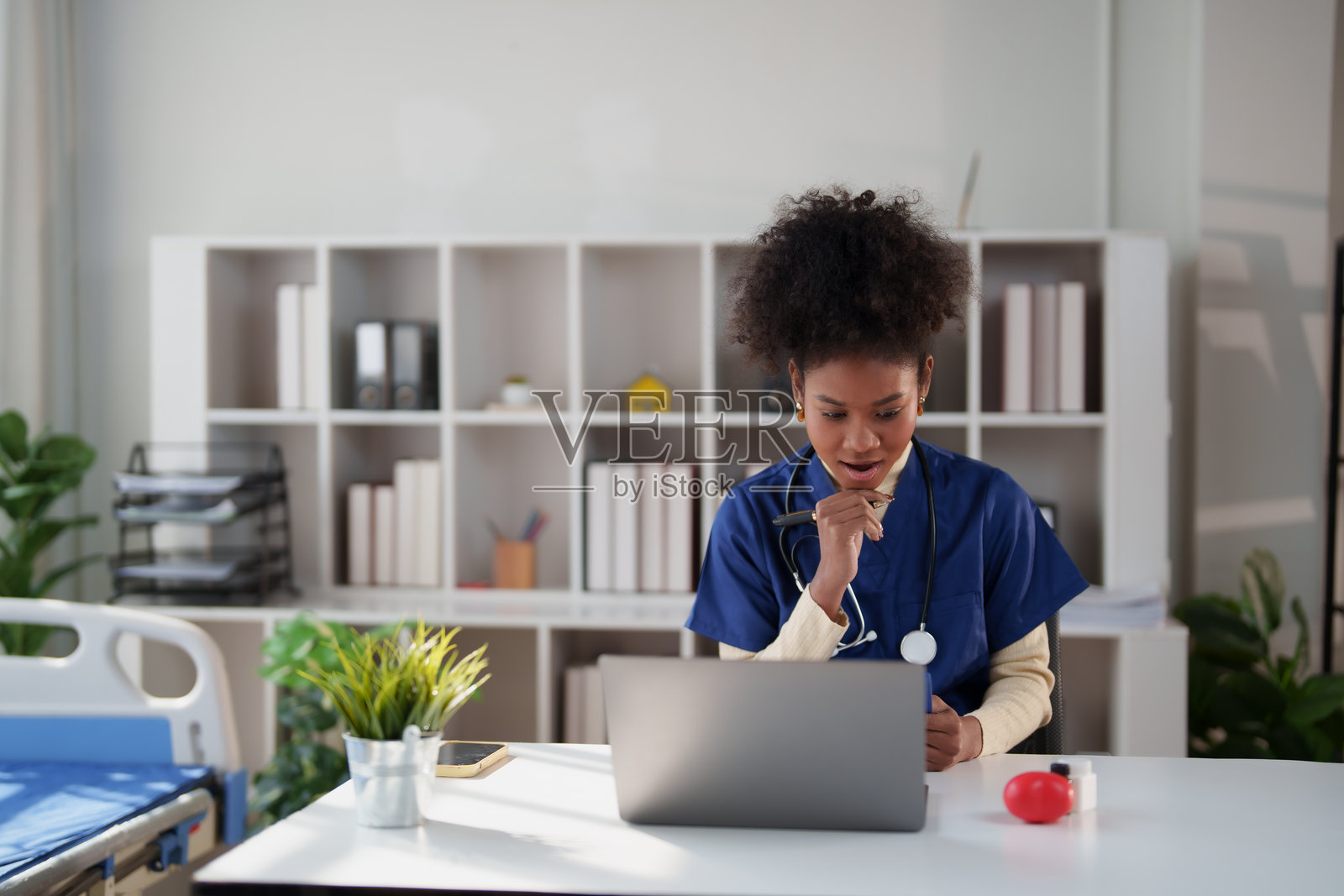 年轻的非裔美国护士在医院办公室使用笔记本电脑提供远程医疗服务，在在线视频通话中关注患者照片摄影图片