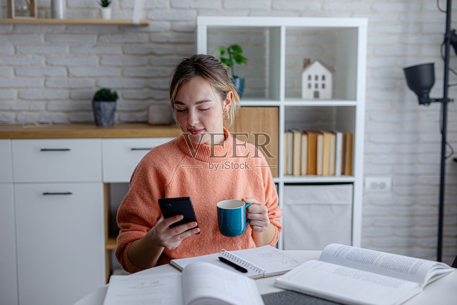 年轻女子在学习间隙喝咖啡并使用手机照片摄影图片