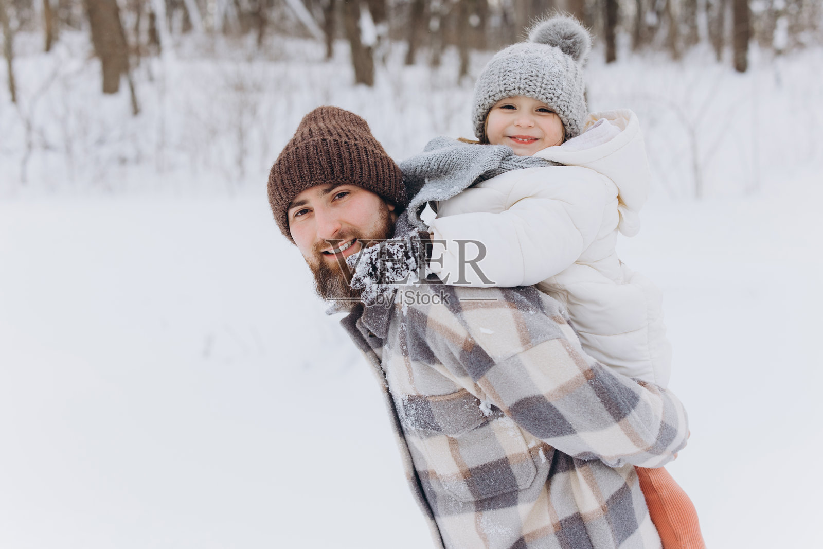 父亲背着女儿享受冬日雪地玩耍的时光照片摄影图片