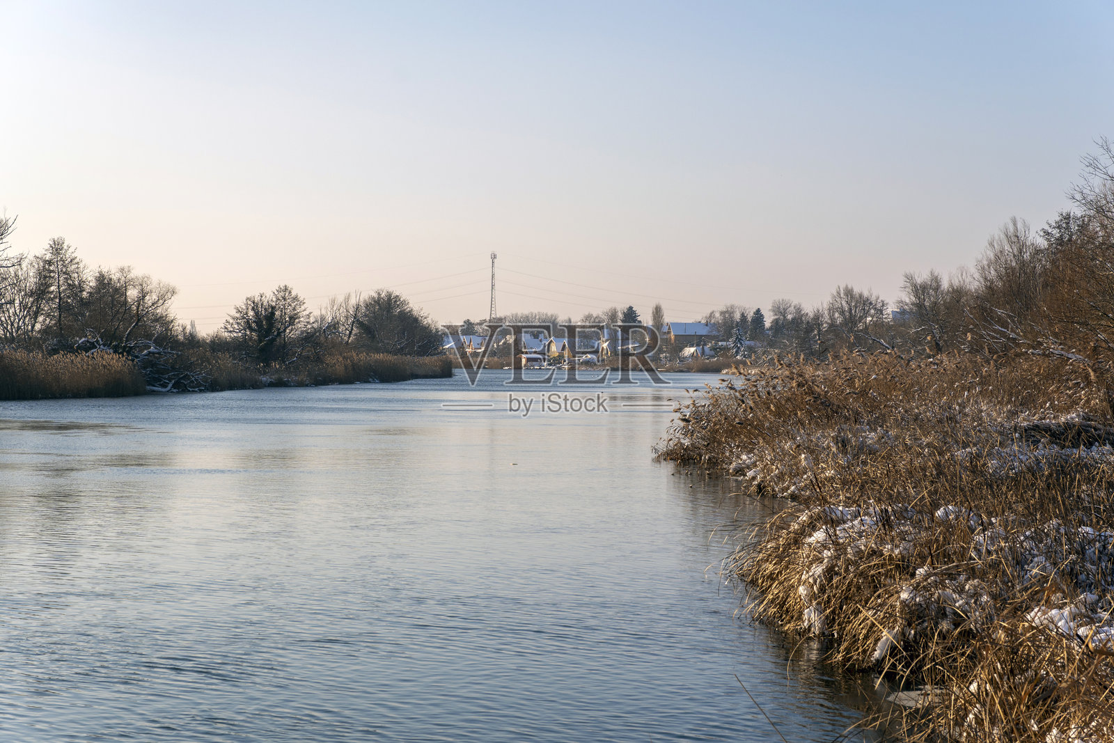 冬日午后，河边景色，背景中有树木和房屋照片摄影图片