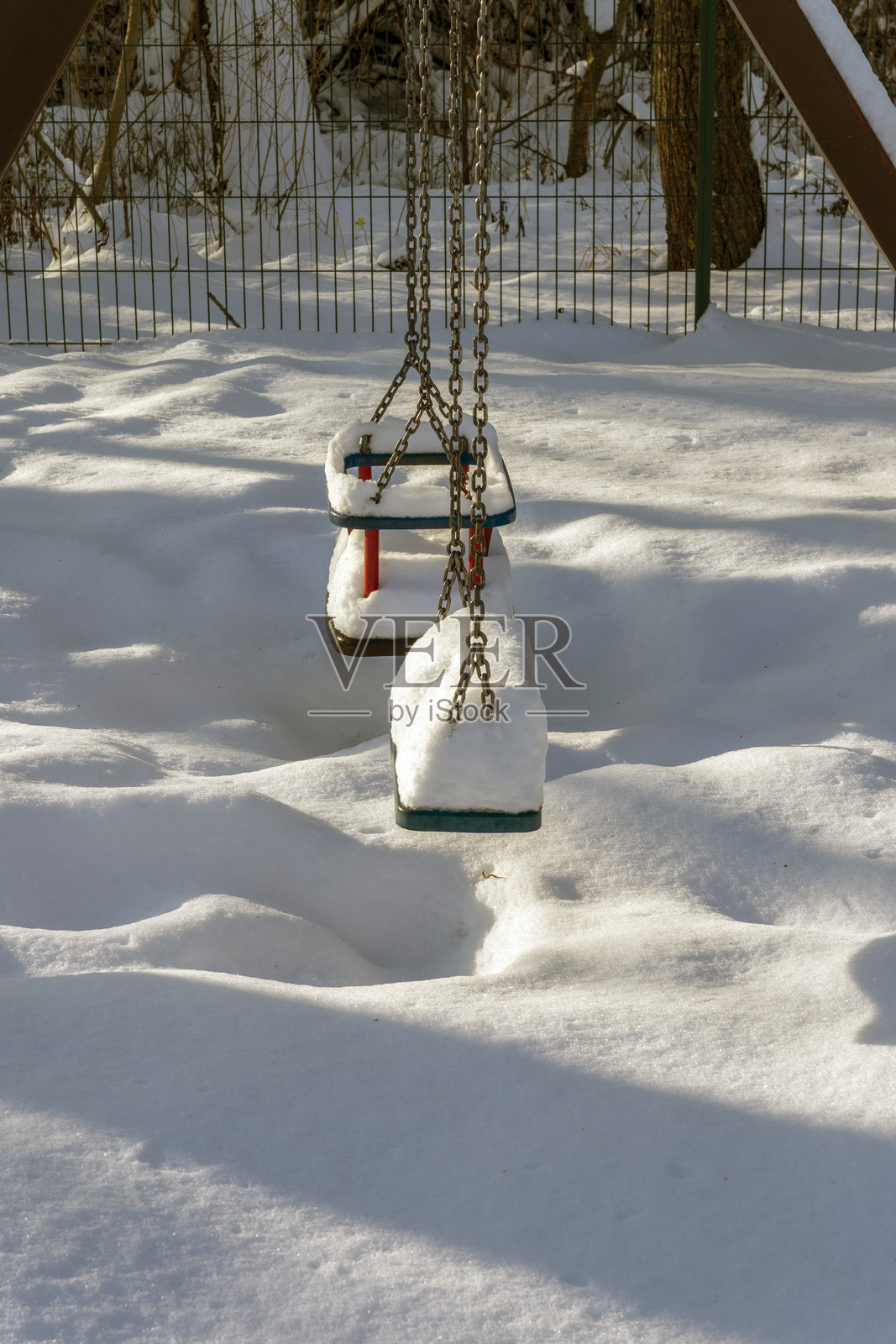 冬日雪景，公园里秋千覆盖着皑皑白雪，四周堆积着厚厚的积雪，展现出一派宁静祥和的景象。照片摄影图片