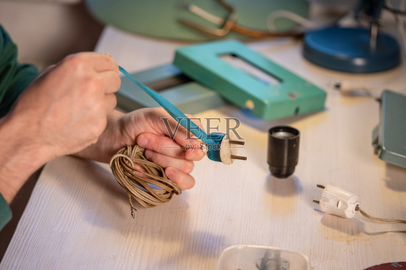 工匠小心地取下缠绕在旧插头上的蓝色电工胶带，进行升级改造和维修照片摄影图片