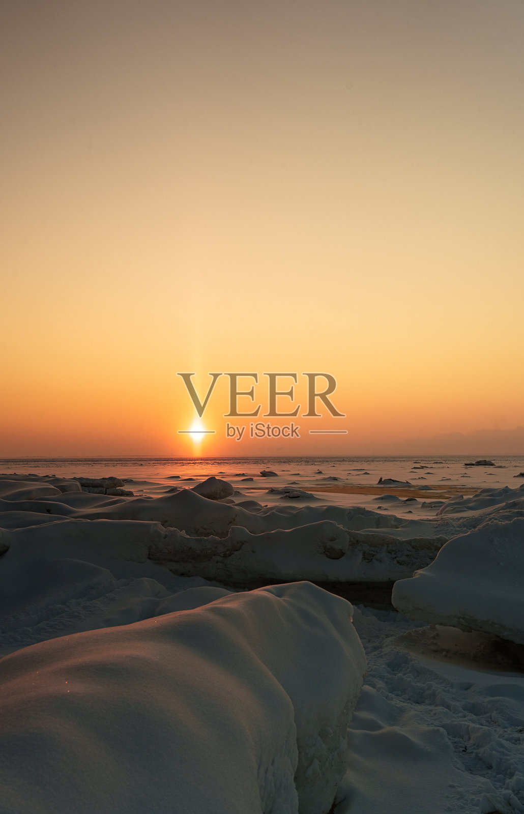 冬季的落日映照在冰冻的雪堆上照片摄影图片