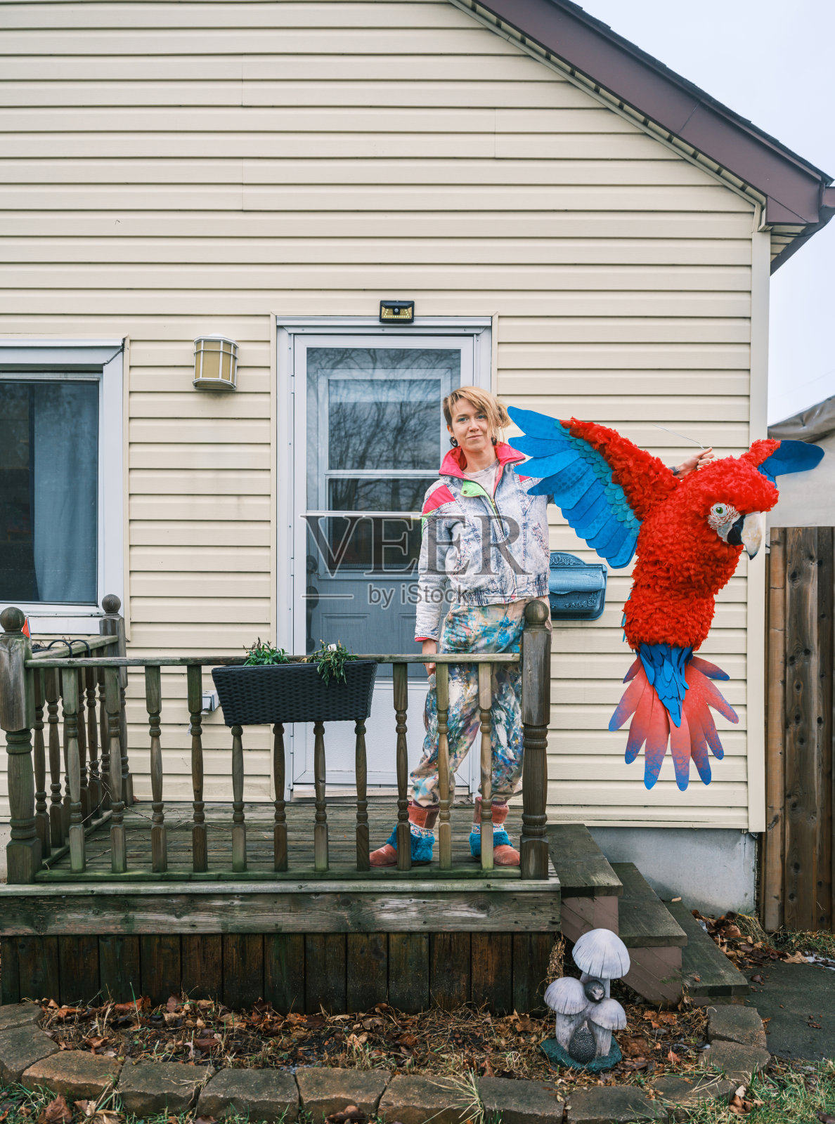 年轻的女艺术家在房子前展示她的纸浆纸鸟照片摄影图片