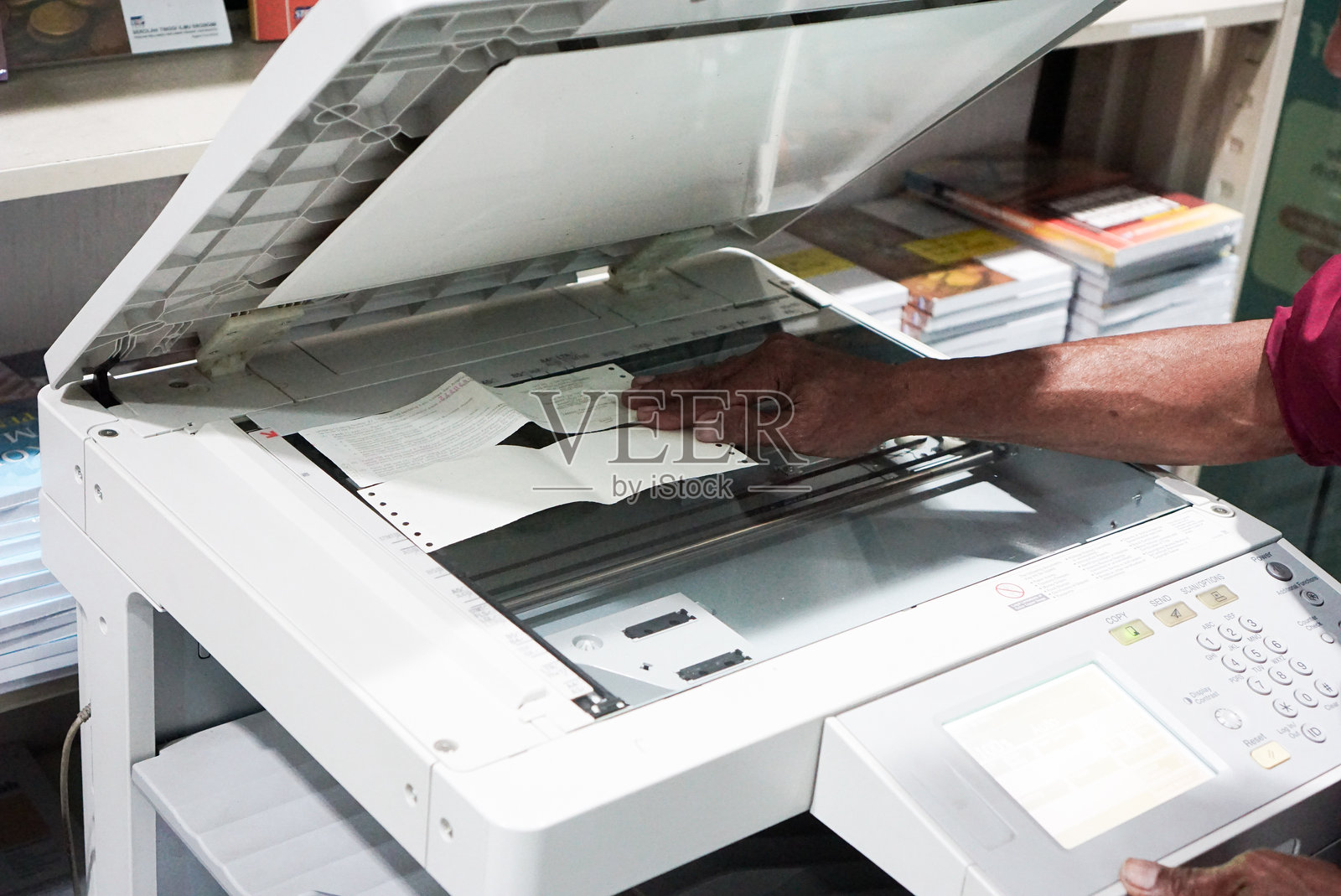 商人在办公室按下操作面板上的按钮使用复印机。照片摄影图片