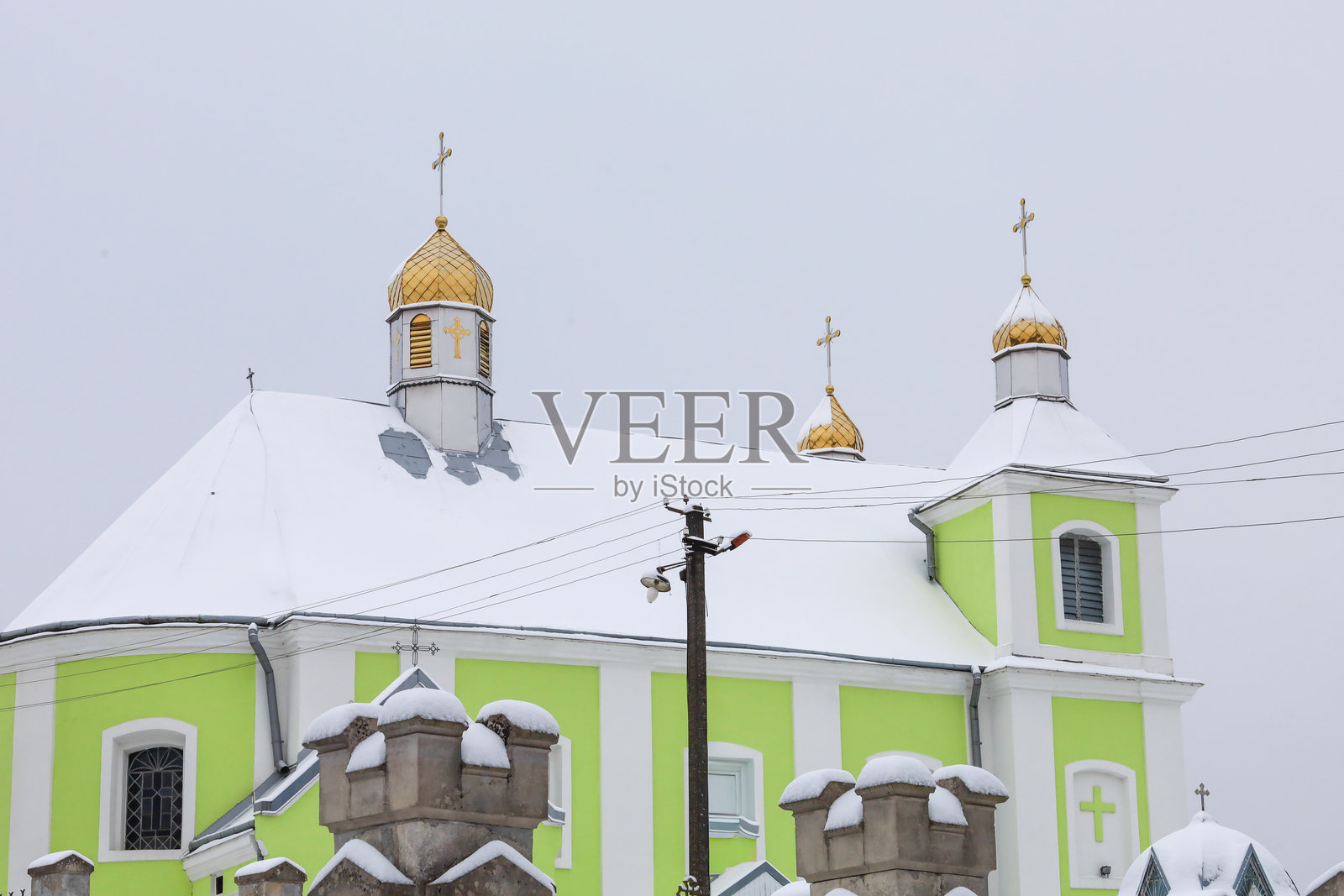 冬季风景，一座东正教教堂，金色圆顶在雪顶和浅绿色墙壁的映衬下闪耀。照片摄影图片