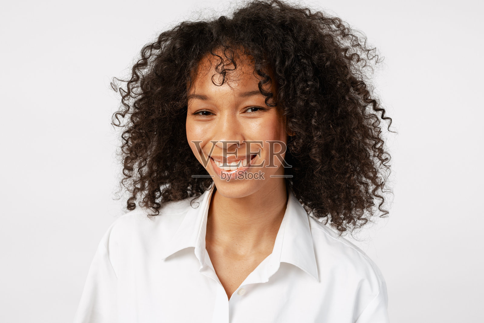 身穿白衬衫的年轻女子，面带微笑，在白色工作室背景前摆姿势照片摄影图片