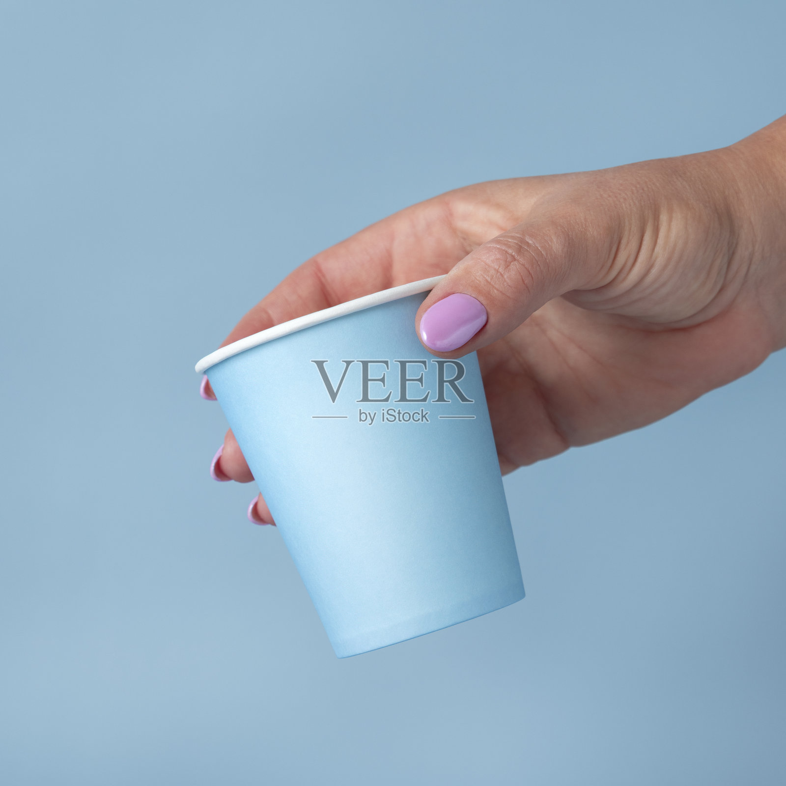 特写镜头，女性手持一次性浅蓝色纸杯，样机，可复制空间。一次性杯照片摄影图片