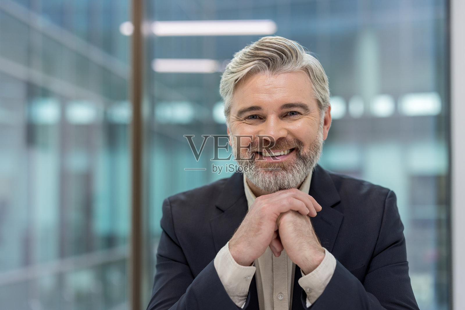 自信的成熟商人面带微笑，在办公室环境中照片摄影图片