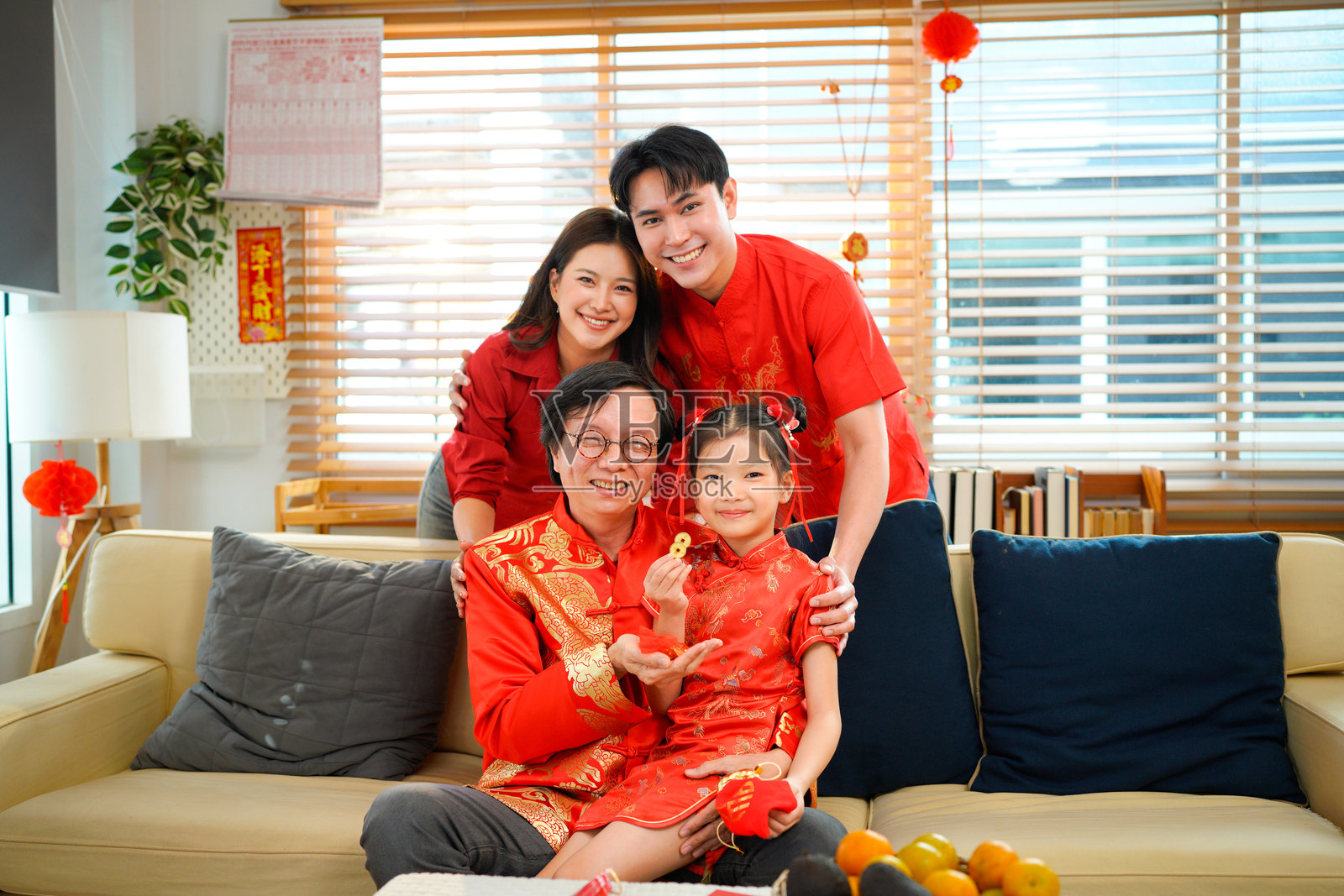 一家四口幸福地微笑着看向镜头，在挂满中国农历新年装饰的现代室内住宅中拍照照片摄影图片