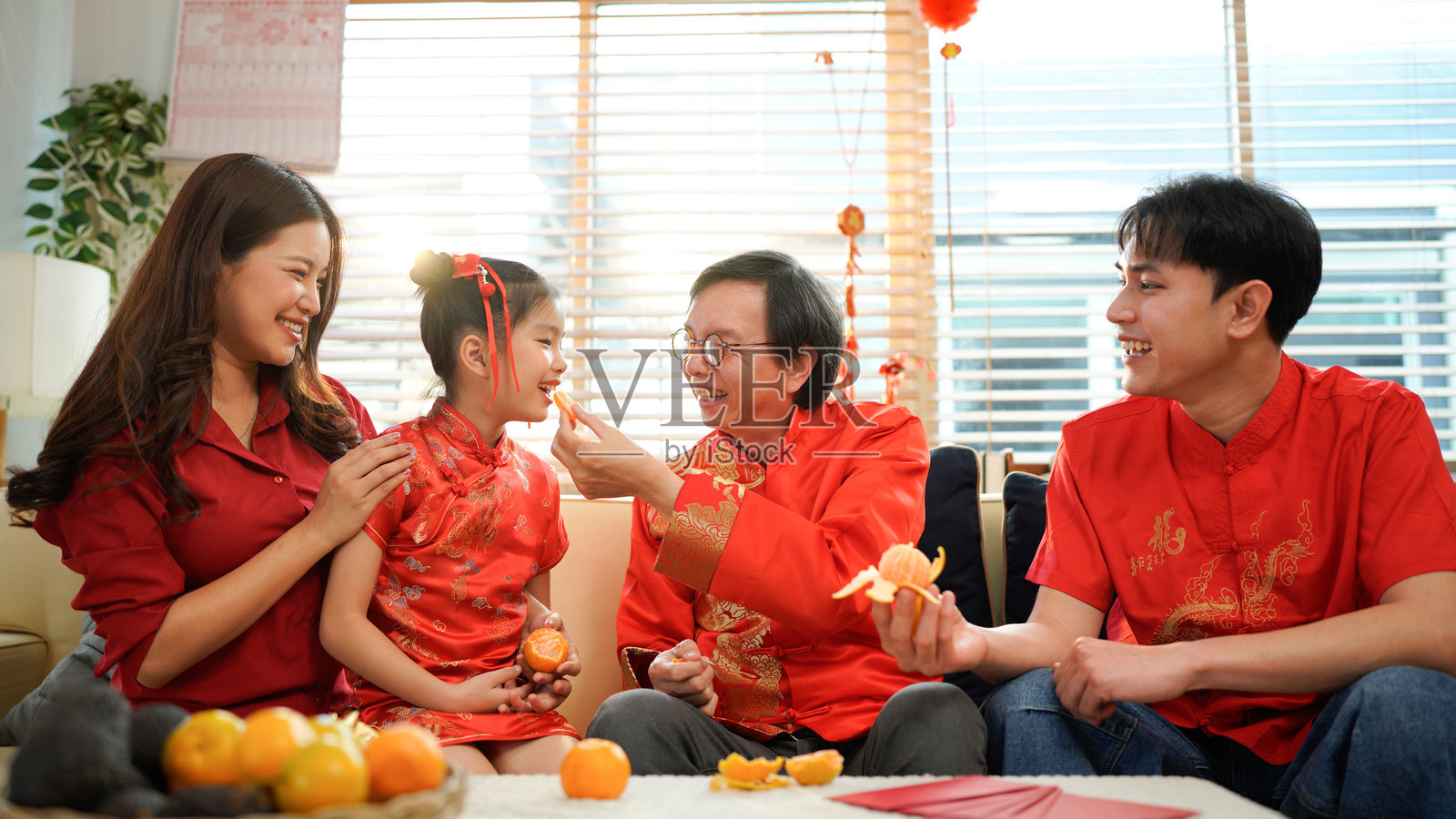 一家亚洲人开心地在家中欢聚，庆祝中国新年，围坐在沙发上交谈，赠送红包并一同用餐。照片摄影图片