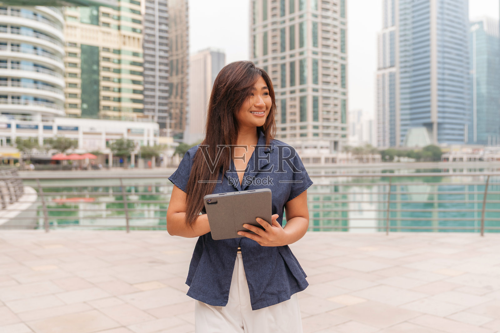 一位亚洲职业女性在现代都市户外使用平板电脑照片摄影图片
