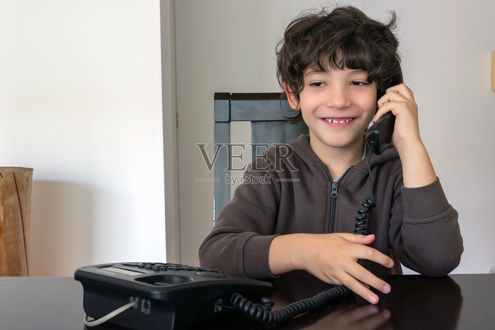 卷发小孩在家中用复古电话交谈和聆听，室内生活方式系列照片摄影图片