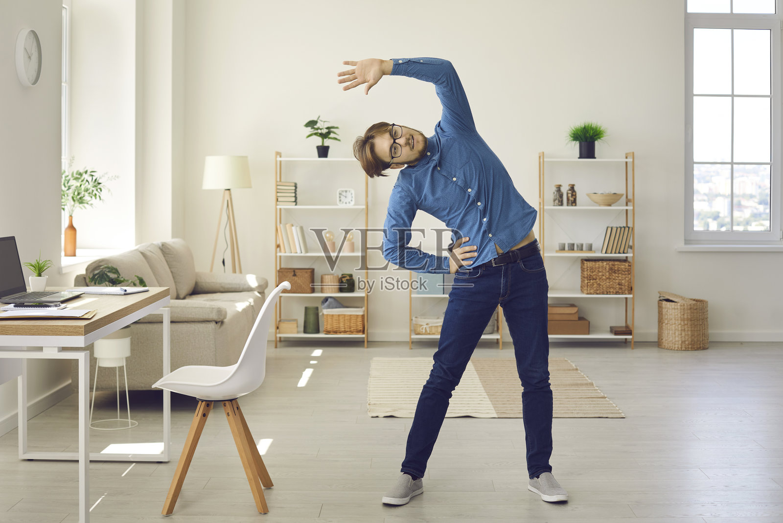 年轻男子在工作或家中进行健身锻炼，同时做伸展运动照片摄影图片