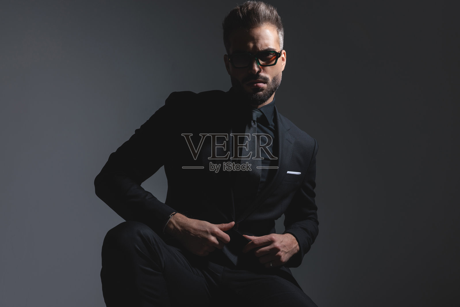 严肃自信的男士正在系黑色西装的纽扣照片摄影图片