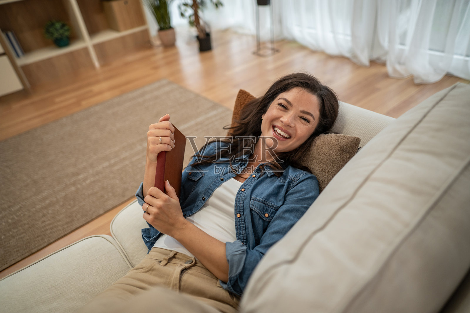 年轻女子在沙发上放松大笑照片摄影图片