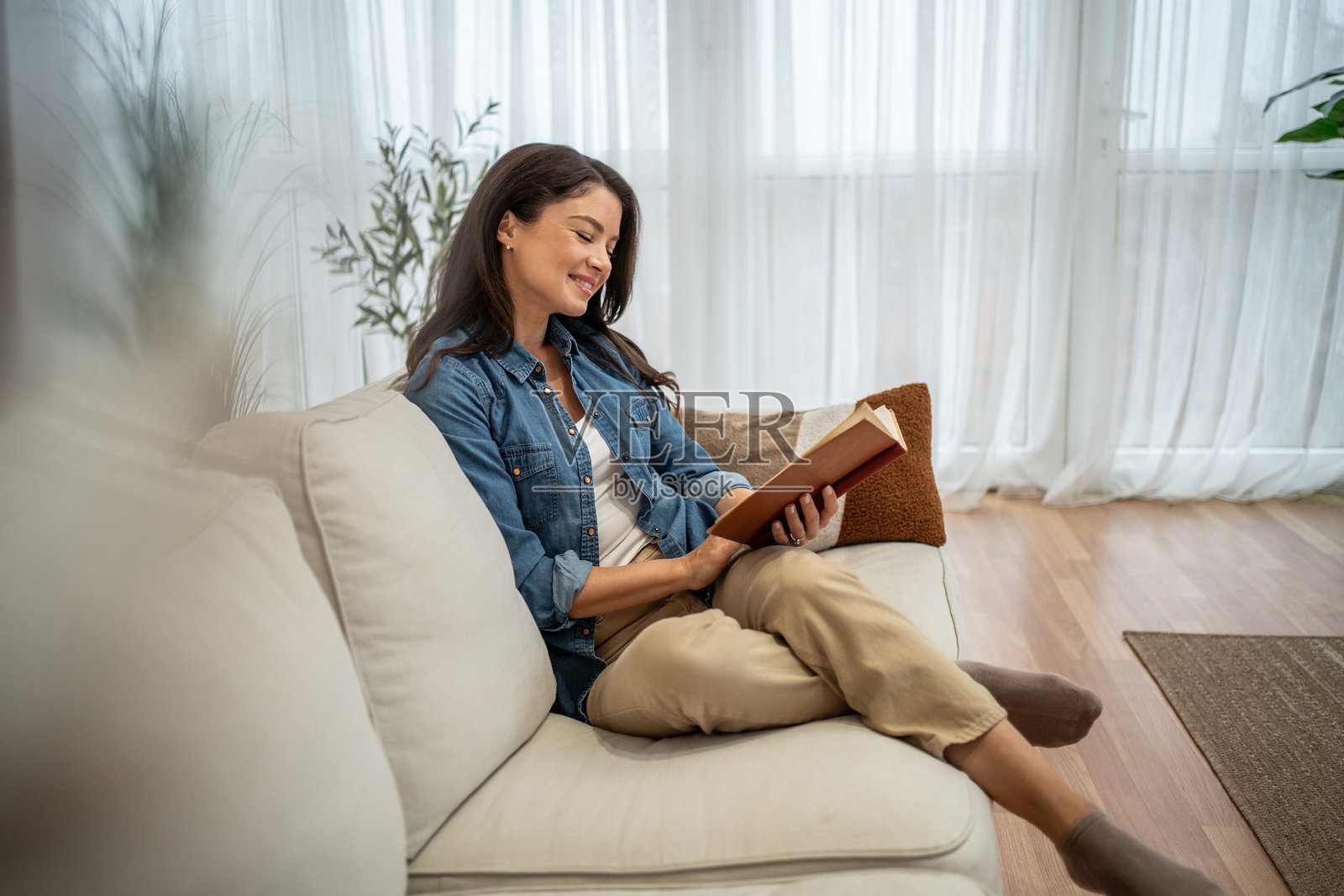 年轻女子在家舒适的沙发上放松地读书照片摄影图片