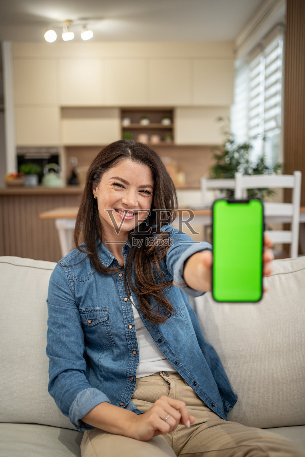 女子手持带有显示应用程序的绿色屏幕的智能手机照片摄影图片
