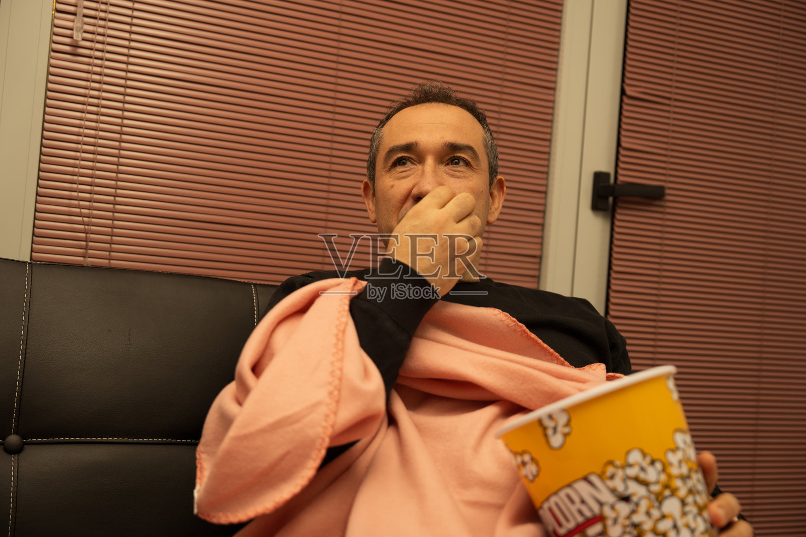 一名成年男子在家看电影时吃爆米花照片摄影图片